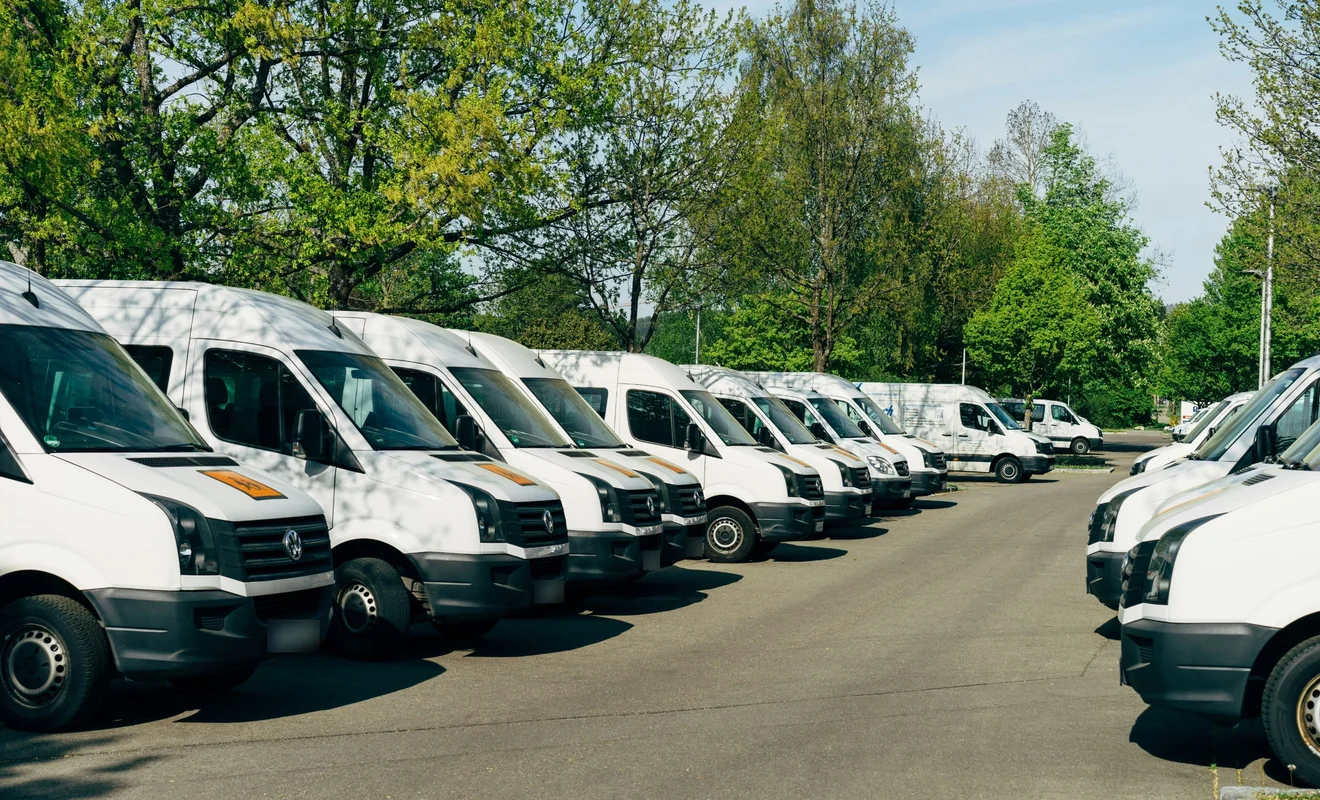 Lange Reihe weißer Transporter auf einem Fuhrpark-Parkplatz